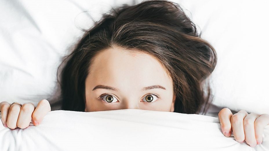 woman covering her face with blanket